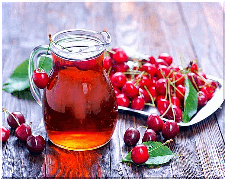 Cherry juice with some cherries next to it.